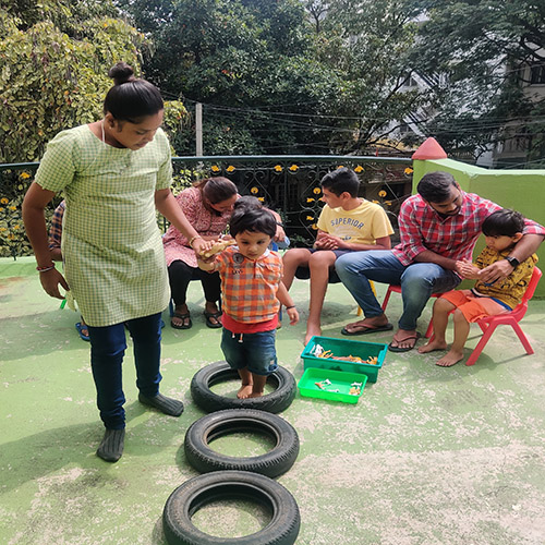 The clinician is making the child walk with the tyres in a straight line and other children are sitting on the chair